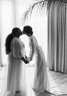 two women standing next to each other in front of a window