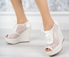 a close up of a person's feet wearing wedges and white shoes with lace on them