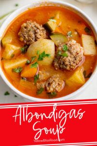 a bowl of soup with meatballs and vegetables in it on a white tablecloth