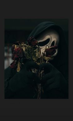 a person wearing a mask and holding a dead rose in their hands with the ghost behind them