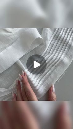 someone is holding up some white fabric to show how it looks like they have been folded