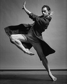 black and white photograph of a man in the air with his arms stretched out while dancing