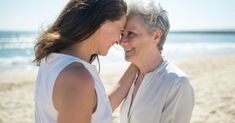 two women standing next to each other on a beach