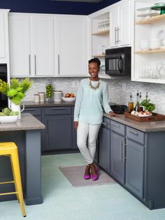 a woman standing in the middle of a kitchen next to a counter top and sink