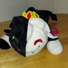 a black and white stuffed animal laying on top of a wooden floor