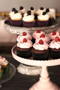 several cupcakes with white frosting and strawberries on top are sitting on a cake stand