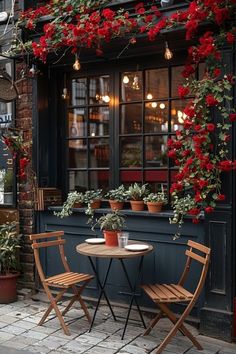 two wooden chairs sitting at a small table in front of a window with red flowers on it