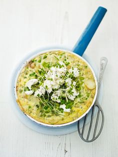 a blue bowl filled with food next to a whisk on top of a table