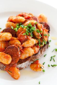 a white plate topped with bread covered in sauce and shrimp on top of tomato sauce