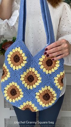 a woman is holding a crocheted bag with sunflowers on the front