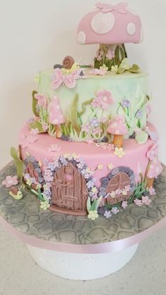 a pink and green cake on top of a white plate with mushrooms, flowers and butterflies