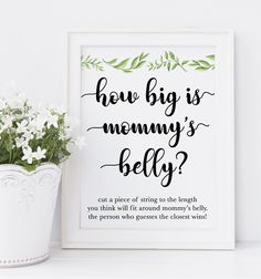 a white vase filled with flowers sitting next to a framed sign that says how big is mommy's belly?