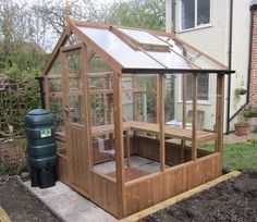 a small wooden greenhouse with a hot tub in the corner and a water tank next to it