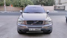 a silver volvo suv parked on the side of a road next to another car in front of a building