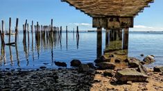 an old pier on the water with rocks under it