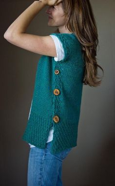 a woman is wearing a green vest with buttons on the front and back, while she has her hands behind her head