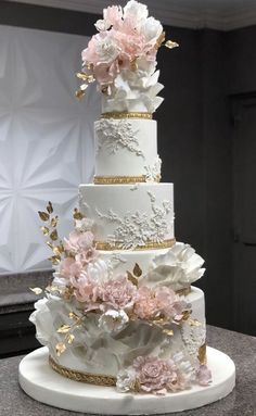 a white and gold wedding cake with flowers on top