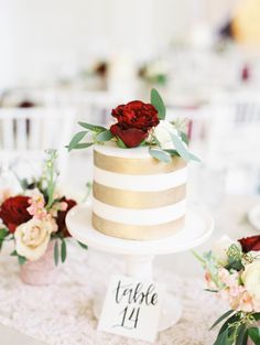 there is a wedding cake with flowers on the table next to it and a place card