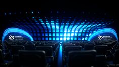 an empty auditorium with rows of seats and blue lights on the walls, in front of a black background