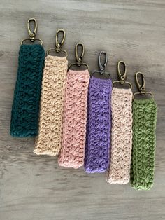 five crocheted key fobs are lined up on a table