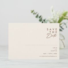 a white business card with the words save the date printed on it next to some flowers