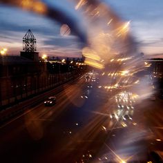 blurry photograph of city street at night with buildings and lights in the foreground