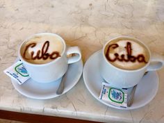 two coffee cups with the word cuba written on them are sitting on a marble table