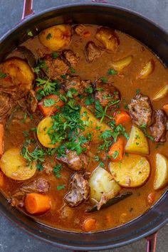 a pot filled with stew and potatoes on top of a table