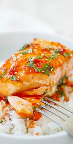 a close up of a plate of food with rice and salmon on it, with a fork in the bowl