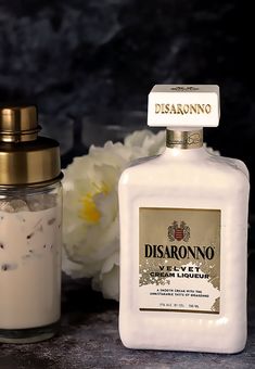 a bottle of disarronno next to a vase with flowers on the table