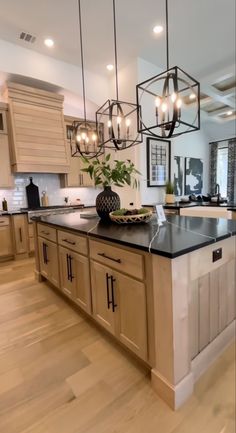 a large kitchen with an island and chandelier hanging from it's ceiling