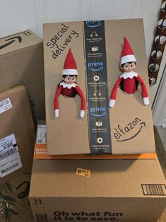 two elfs are sitting on top of boxes with the same package in front of them