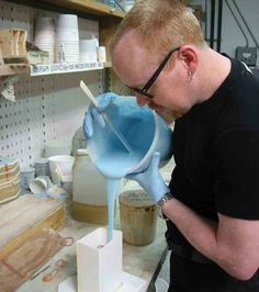 a man in glasses is pouring blue liquid into a bowl