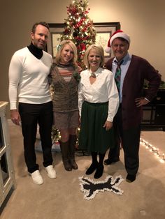 three people standing in front of a christmas tree