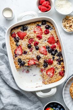 a cake with berries, blueberries and almonds in it on a white table