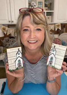 a woman holding up two small cards with a church on them in front of her face