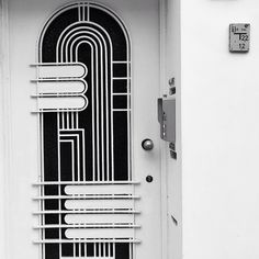 a white door with a black and white design on the front panel, next to a clock