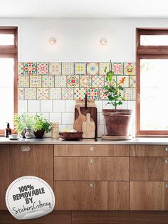 a kitchen with wooden cabinets and plants on the counter top in front of two windows