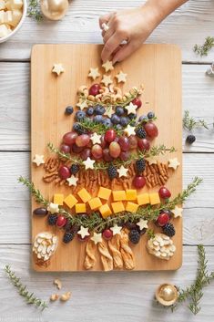 a christmas tree made out of crackers and grapes on a cutting board with other snacks