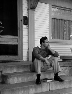 a man sitting on steps in front of a house with his hand under his chin