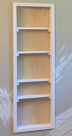 a white shelf with three shelves on the top and bottom, against a gray wall