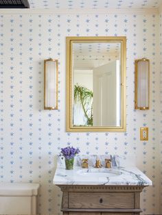 a bathroom sink with a mirror above it and a vase on the counter next to it