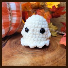 a white crocheted object sitting on top of a wooden table next to autumn leaves