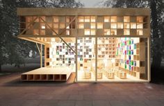 a wooden structure with many bookshelves on the outside and inside, lit up at night