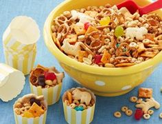 a yellow bowl filled with cereal next to small cups full of candy and candies