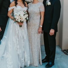 a group of people standing next to each other in front of a wall wearing formal wear