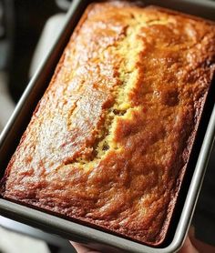 a person holding a loaf of banana bread in a pan on top of a stove