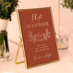 a wedding guest book on a table with flowers and vases in the back ground