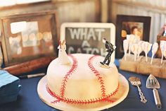 a baseball themed wedding cake is displayed on a table with utensils and pictures