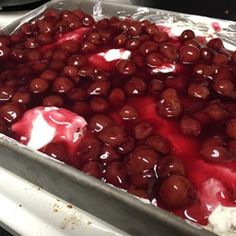 a pan filled with red and white desserts on top of a stove covered in tin foil